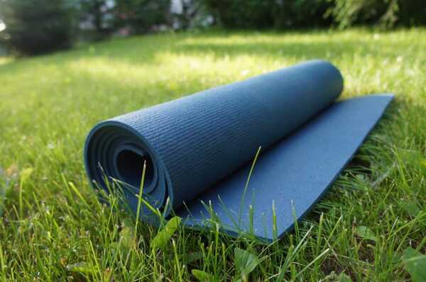 Tapete de yoga enrollado junto a una planta